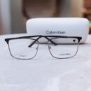 Armação de Óculos Masculina CALVIN KLEIN em Metal - Cor: Preto com Detalhes Metálicos em Rosé - Formato: Retangular, com Cantos levemente Suavizados